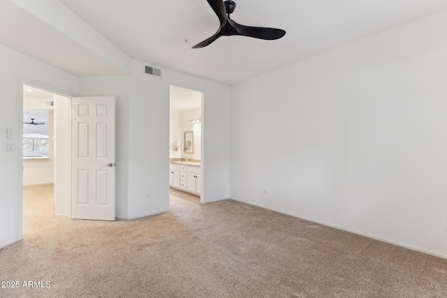 unfurnished bedroom featuring light carpet, ceiling fan, and ensuite bath