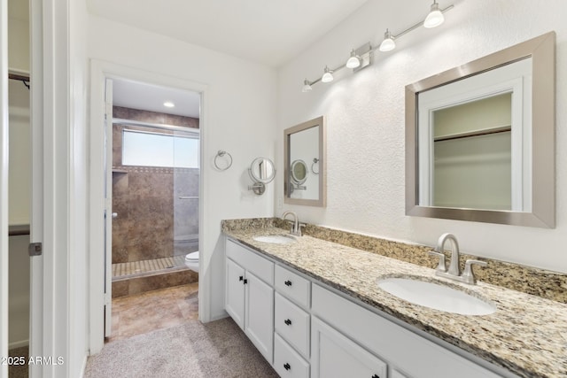 bathroom with tiled shower, vanity, and toilet