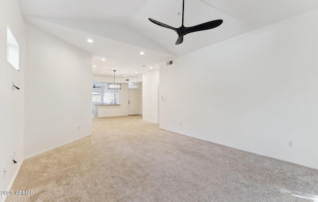 unfurnished living room with light colored carpet, lofted ceiling, and ceiling fan with notable chandelier