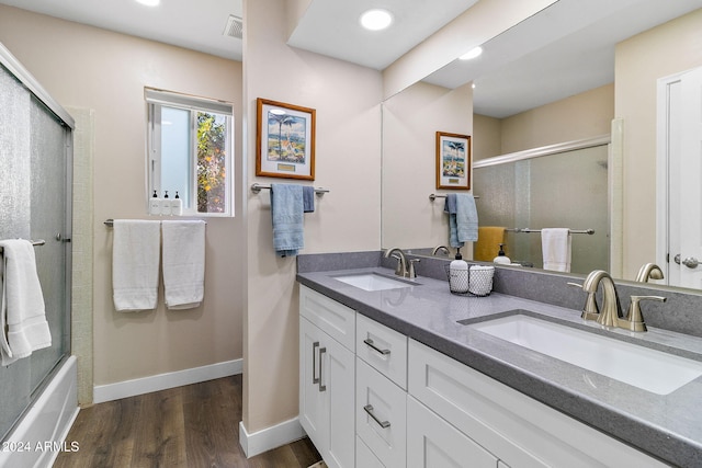 bathroom featuring hardwood / wood-style floors, vanity, and enclosed tub / shower combo