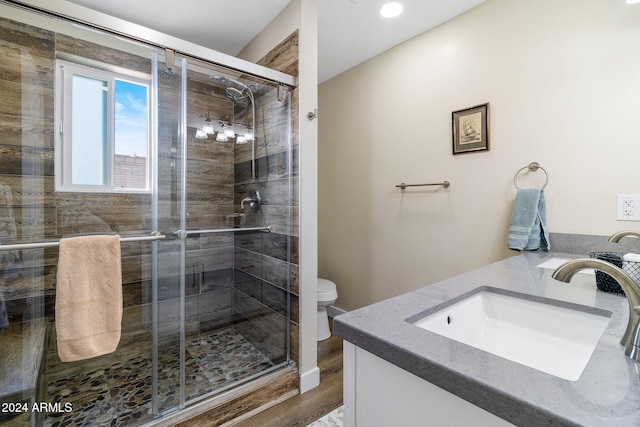 bathroom featuring hardwood / wood-style floors, vanity, toilet, and an enclosed shower