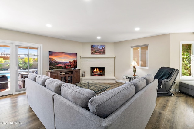 living room featuring a wealth of natural light, wood-type flooring, and a brick fireplace