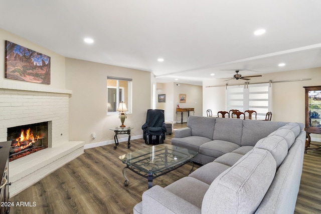 living room featuring ceiling fan, hardwood / wood-style floors, and a brick fireplace