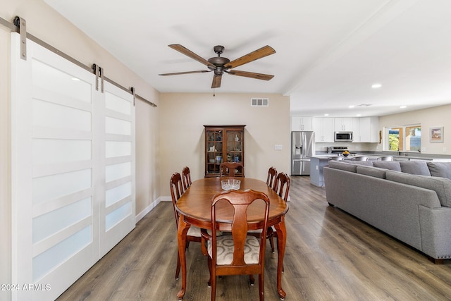 dining space featuring hardwood / wood-style flooring, ceiling fan, and a barn door