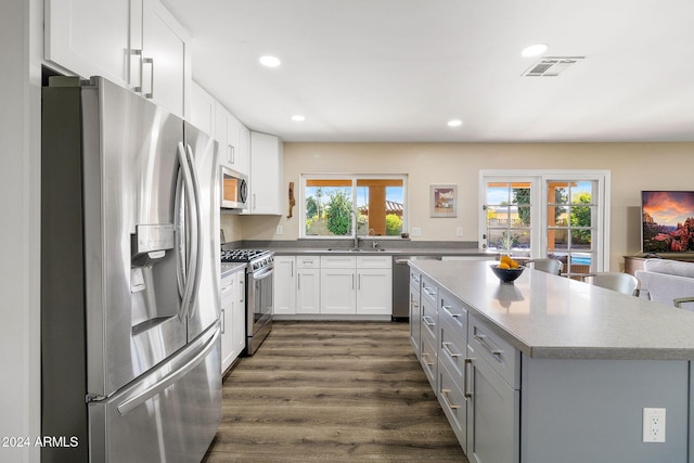 kitchen with a center island, sink, dark hardwood / wood-style flooring, white cabinets, and appliances with stainless steel finishes