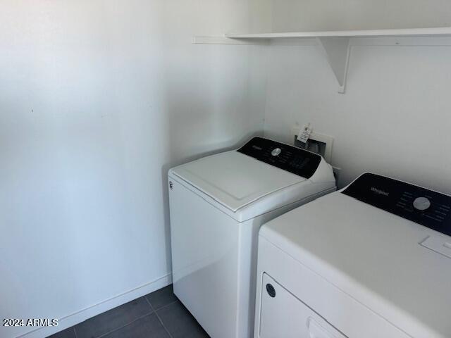 laundry room with washer and clothes dryer and dark tile patterned flooring