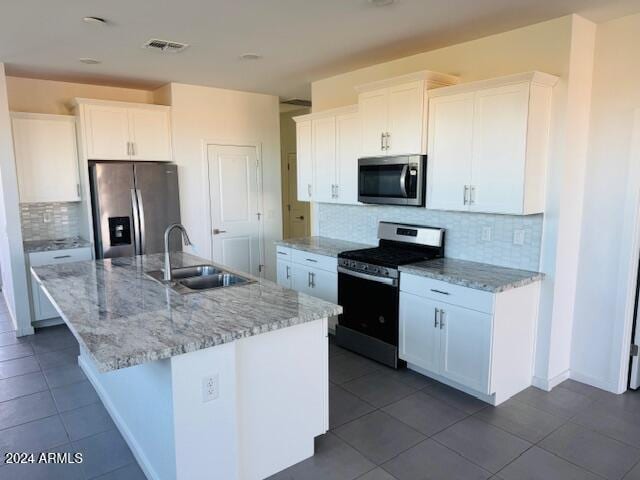 kitchen featuring white cabinetry, sink, stainless steel appliances, backsplash, and a kitchen island with sink