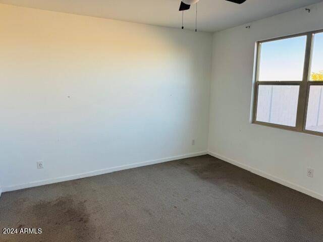 unfurnished room with ceiling fan and dark carpet