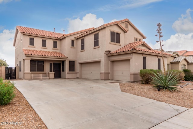 mediterranean / spanish house featuring a garage, driveway, a tile roof, fence, and stucco siding