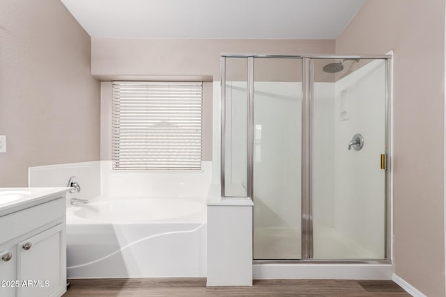 bathroom featuring a garden tub, a shower stall, wood finished floors, and vanity