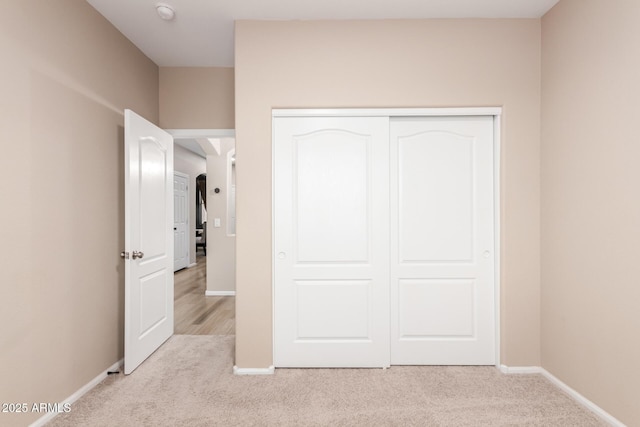 unfurnished bedroom with carpet floors, a closet, and baseboards