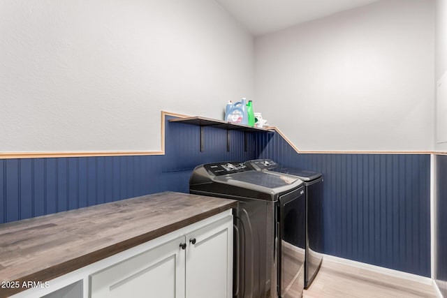 washroom with a wainscoted wall, separate washer and dryer, and light wood-type flooring