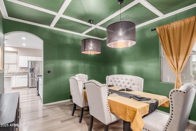 dining space featuring arched walkways, visible vents, light wood-style floors, coffered ceiling, and baseboards