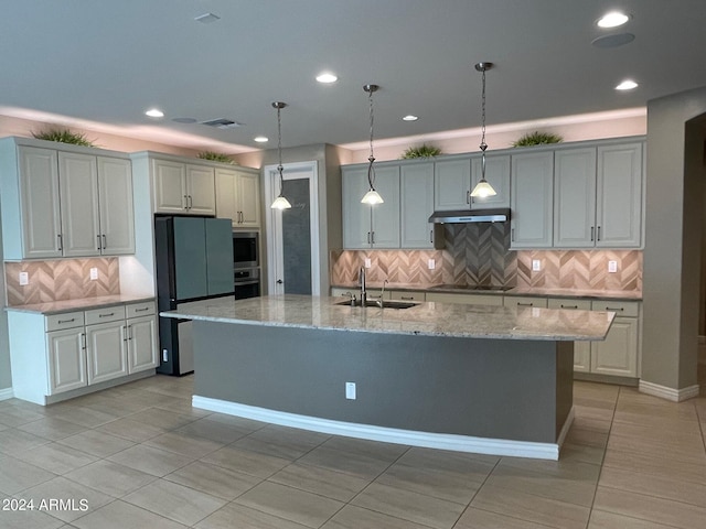 kitchen featuring sink, stainless steel oven, refrigerator, a kitchen island with sink, and light tile patterned floors