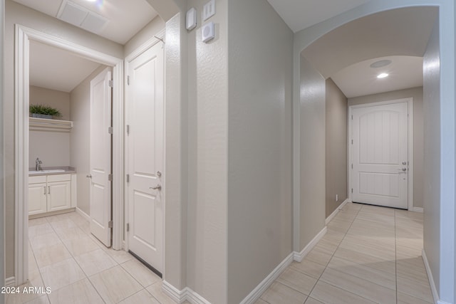 corridor with light tile patterned floors and sink