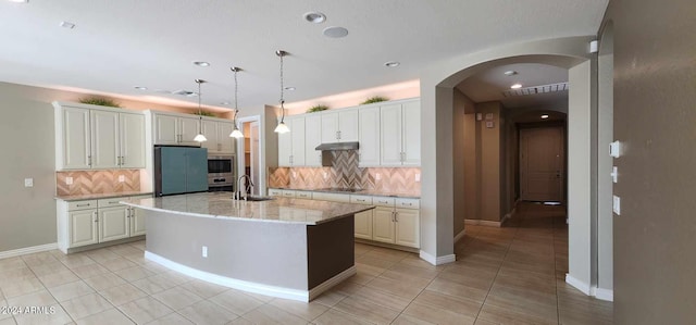 kitchen with backsplash, white cabinetry, and a kitchen island with sink