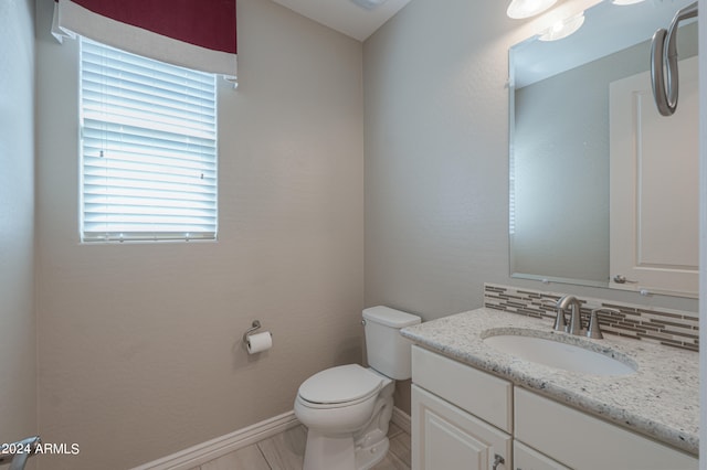 bathroom with vanity, backsplash, toilet, and plenty of natural light