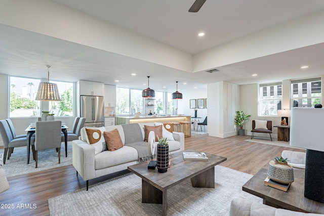 living room featuring ceiling fan, light hardwood / wood-style floors, and sink