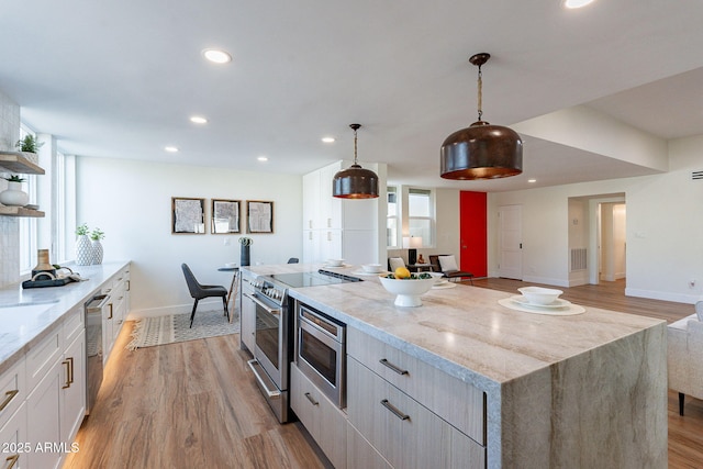 kitchen featuring appliances with stainless steel finishes, light hardwood / wood-style floors, plenty of natural light, and hanging light fixtures