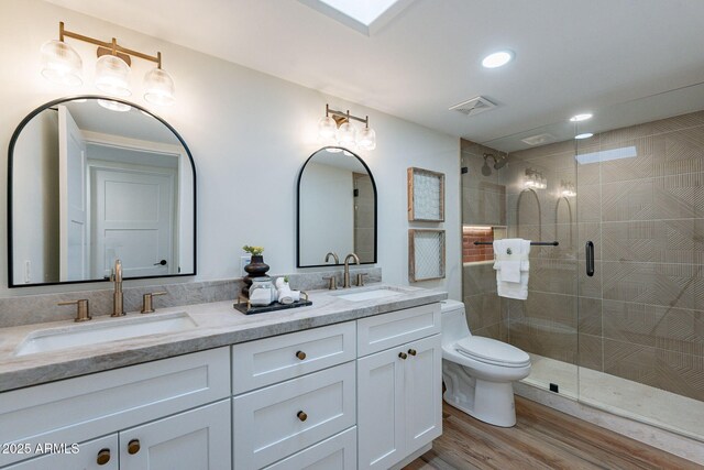 bathroom with hardwood / wood-style floors, vanity, an enclosed shower, and toilet