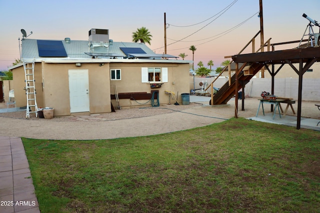 2014 N 17th Pl, Phoenix, AZ 85006 - back of property at dusk with stucco siding, a patio area, roof mounted solar panels, and a fenced backyard