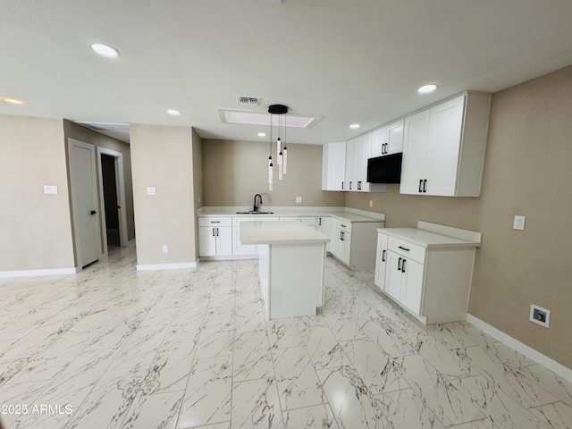 kitchen with marble finish floor, a kitchen island, visible vents, and baseboards