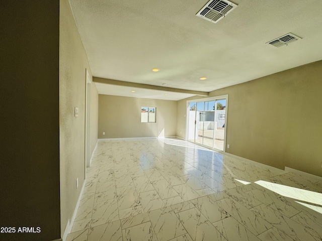 empty room with marble finish floor, baseboards, visible vents, and a textured ceiling