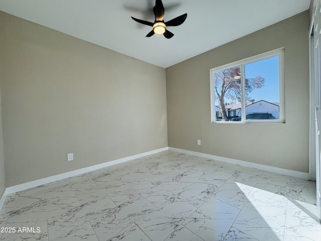 unfurnished room with marble finish floor, a ceiling fan, and baseboards