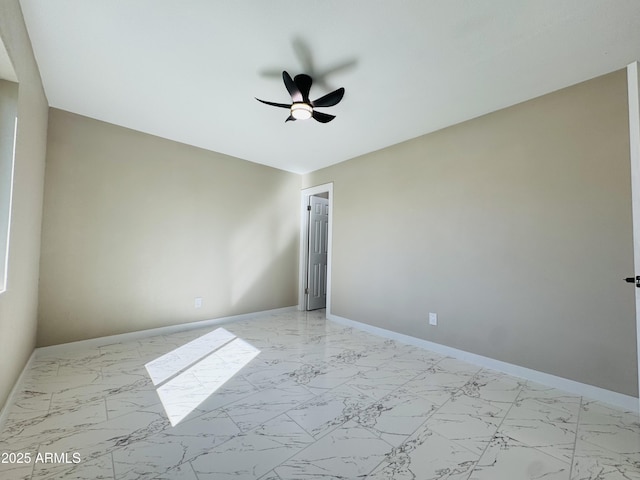 spare room with marble finish floor, baseboards, and a ceiling fan