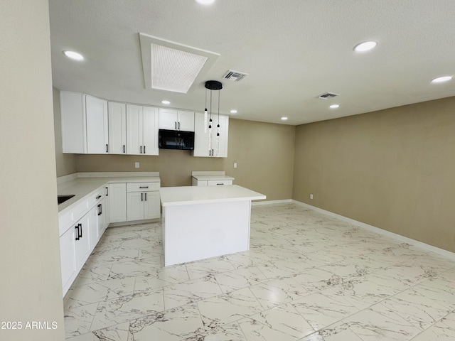 kitchen featuring white cabinetry, marble finish floor, visible vents, and black microwave