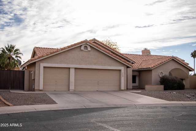 mediterranean / spanish home featuring a tile roof, a chimney, stucco siding, a garage, and driveway