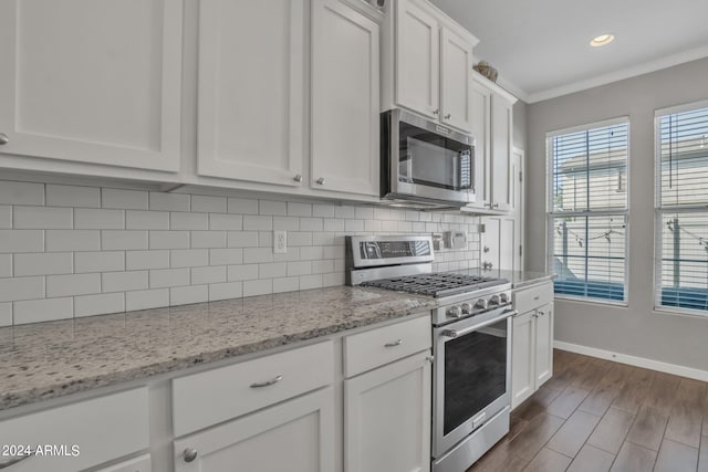 kitchen with white cabinetry, crown molding, stainless steel appliances, light stone countertops, and backsplash