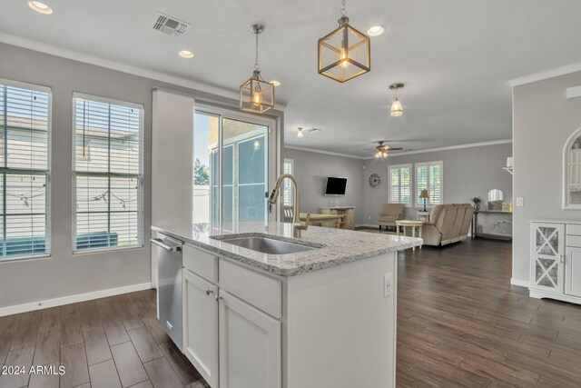 kitchen with pendant lighting, sink, white cabinets, light stone counters, and a center island with sink