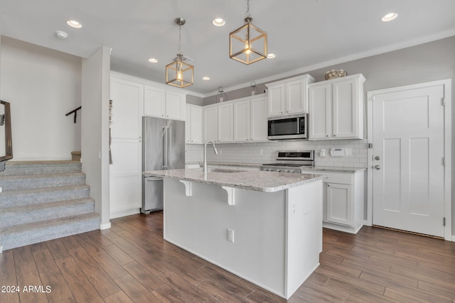 kitchen with sink, white cabinets, hanging light fixtures, a kitchen island with sink, and stainless steel appliances