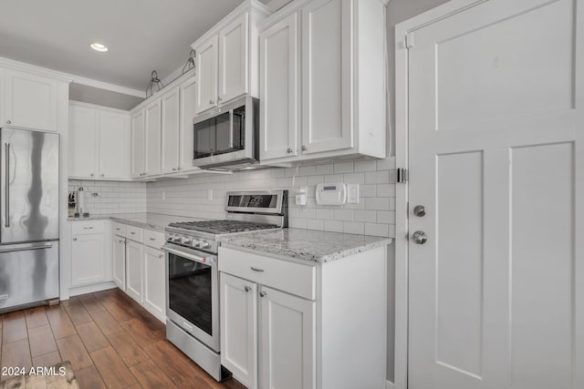 kitchen with high end appliances, dark hardwood / wood-style flooring, ornamental molding, light stone counters, and white cabinets