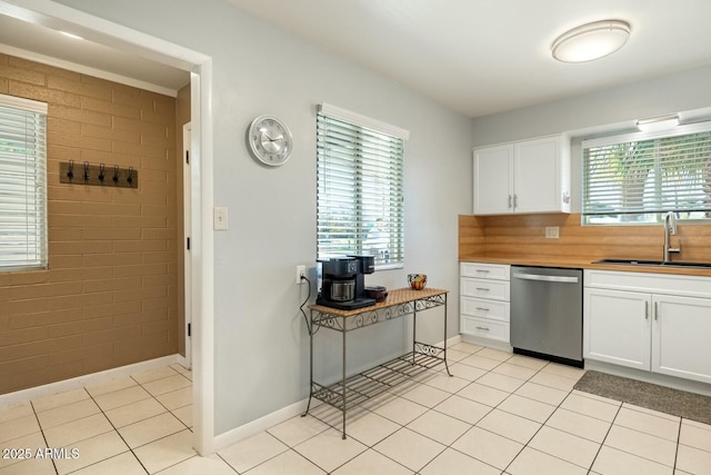 kitchen featuring white cabinetry, a sink, stainless steel dishwasher, and light tile patterned floors