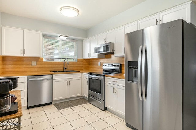 kitchen with white cabinets, decorative backsplash, stainless steel appliances, and a sink