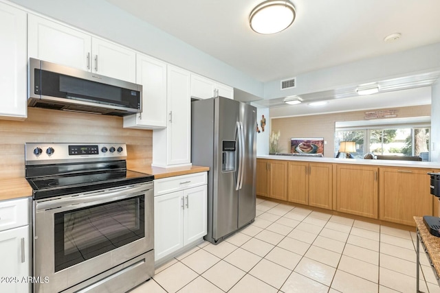 kitchen featuring appliances with stainless steel finishes, visible vents, decorative backsplash, and white cabinetry