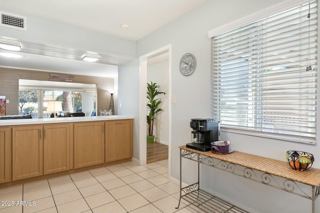 interior space with light tile patterned floors, baseboards, visible vents, and light countertops