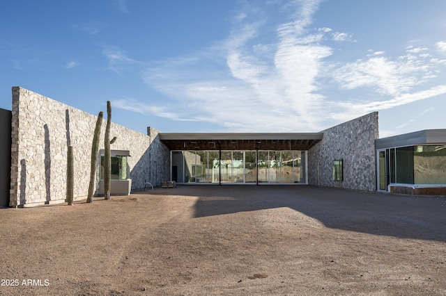 back of house with driveway, a carport, and stucco siding