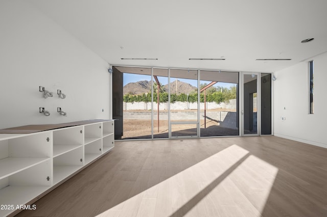 unfurnished living room featuring rail lighting, floor to ceiling windows, and wood finished floors