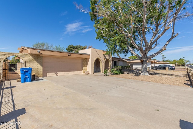 view of front of property featuring an attached garage, a gate, fence, and concrete driveway