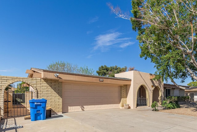 view of front of home featuring a gate, brick siding, an attached garage, and concrete driveway