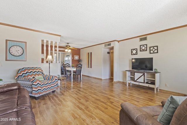 living room with wood-type flooring, ornamental molding, ceiling fan, and a textured ceiling