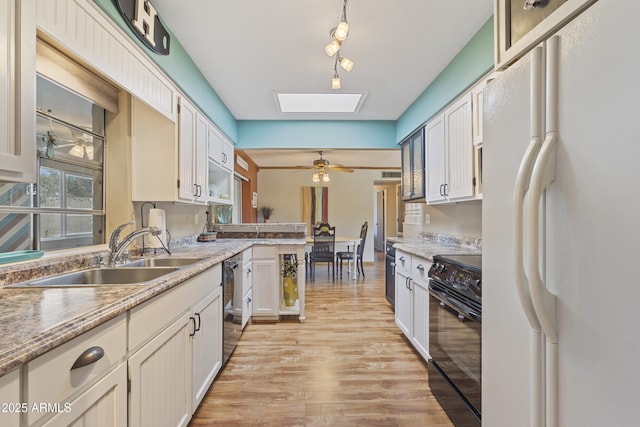 kitchen featuring sink, white refrigerator, black / electric stove, light hardwood / wood-style floors, and white cabinets