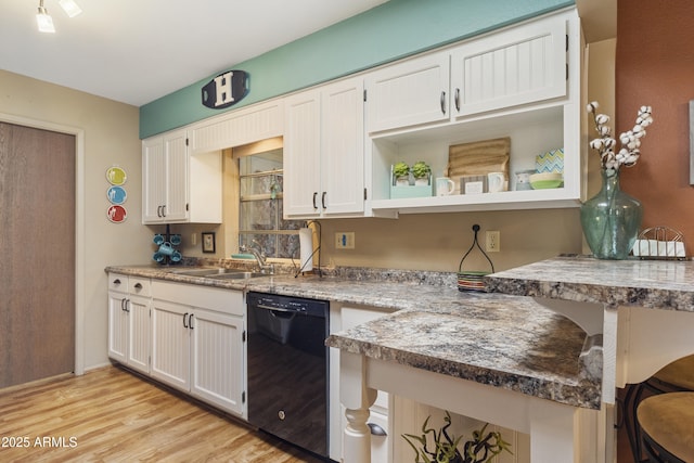 kitchen featuring sink, dishwasher, white cabinetry, light stone counters, and light wood-type flooring