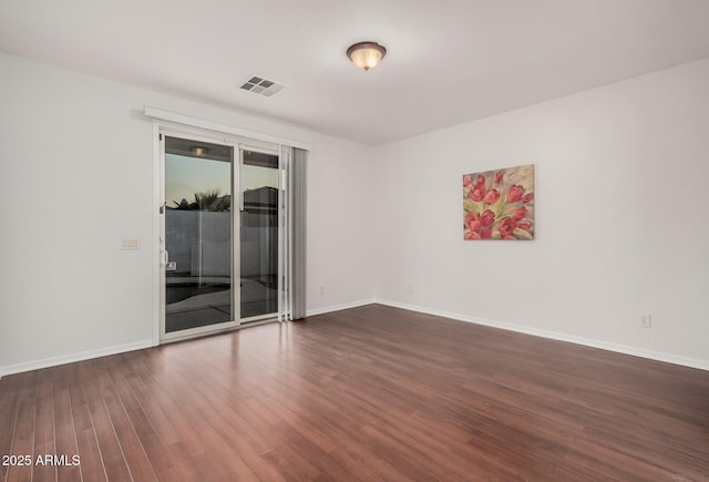 unfurnished room featuring visible vents, dark wood finished floors, and baseboards