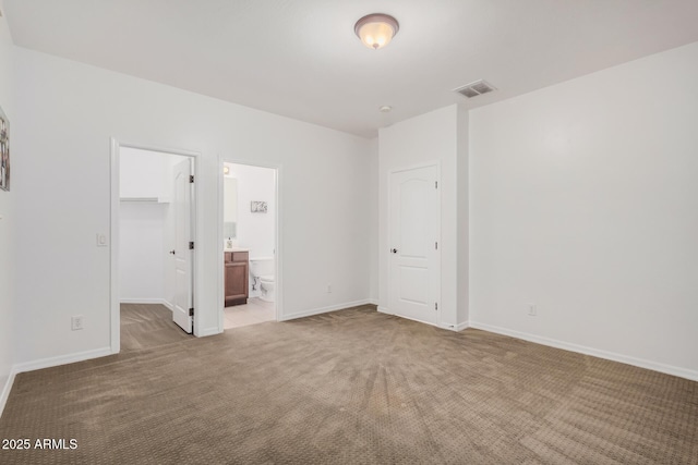 unfurnished bedroom featuring light carpet, baseboards, visible vents, a walk in closet, and a closet