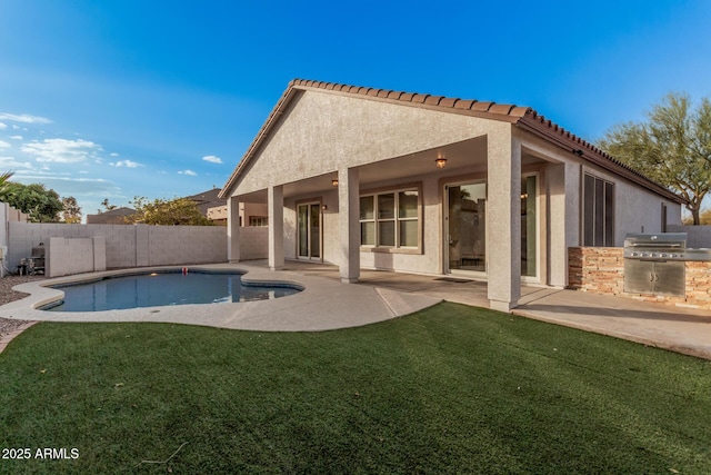 rear view of house featuring a lawn, a fenced in pool, exterior kitchen, and a patio