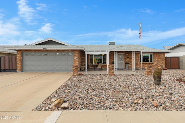 single story home with brick siding, concrete driveway, a garage, and a gate